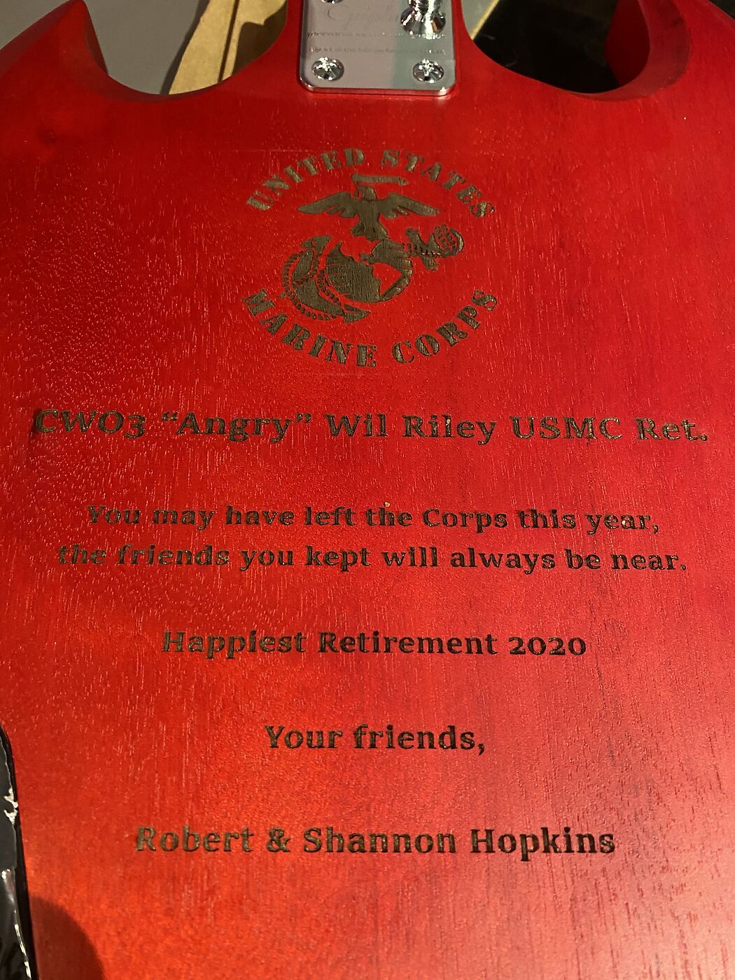 Red wood plaque engraved with the Marine Corps emblem and a retirement message