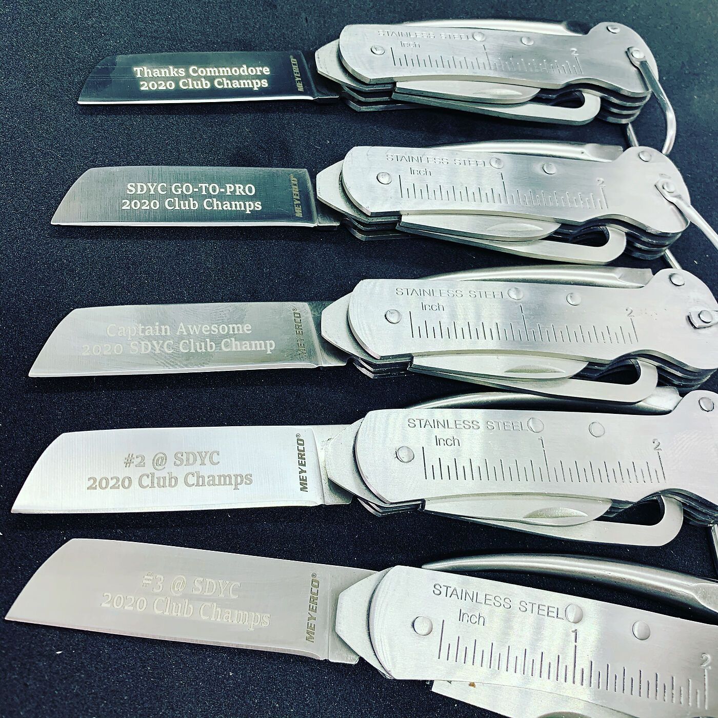 Row of San Diego Yacht Club champion pocket knives with engraved blades